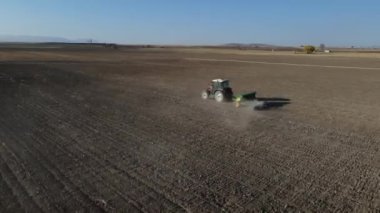 Aerial drone view of tractor tilling the land, working with tractor in farmland, image of tractor hoeing soil leaving dust, farming with tractor