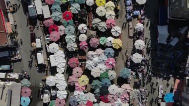 Drone footage of shopping markets set up on the street, street shopping covered with umbrellas and tents, shopping tents set up on the road between the apartments