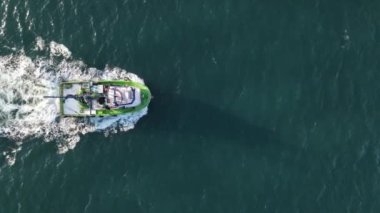 Drone view of small ship foaming in the sea, fishing boat fishing from the sea with nets, colorful boats on turquoise water