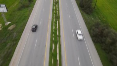 Drone view of traffic density flowing in TRNC left lane, traffic flowing in green fields, vehicles driving