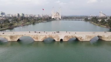 Drone view of the historical stone bridge and the great Sabanci mosque that has dried over the river, the view of the city of adana on the river