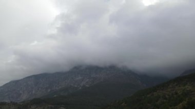 Drone view of dense fog cloud on top of high mountains, mist cloud in the air, cold weather conditions in nature