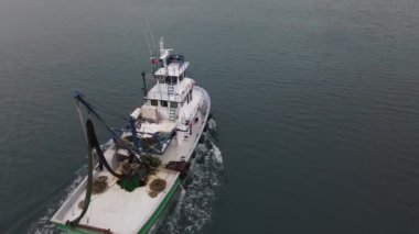 Drone footage of white fishing boat in the middle of the sea, fishing with nets, fishing seafood, white boat in the lake