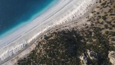 Salda lake with white beach surrounded by trees, touristic crater lake, drone view of the Salda, the volcanic lake with its white sand and turquoise waters in Burdur