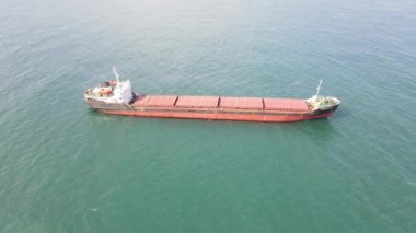 Drone view of cargo ship carrying cargo in the middle of the sea, red cargo carrier on turquoise sea, ship providing maritime trade in Blacksea