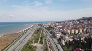 Aerial drone view of the coastal city of Trabzon, the city located on the coastline, the blocks of apartments facing the sea, mountains behind it and the city overlooking the black sea