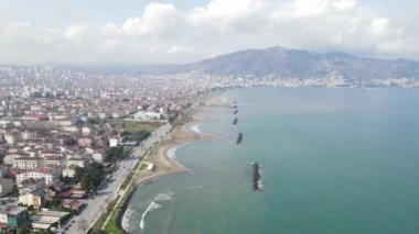 Aerial drone view of seaside cityscape Ordu, city by the coast, view of the city built by the sea, waves crashing on the shore of the foamy sea