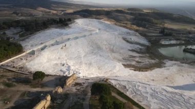 Drone view of Pamukkale travertines, natural beauty consisting of waterfalls and swimming pool with white minerals in Turkey, white travertines on one side of the mountain