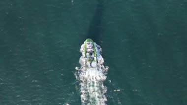 Drone view of small ship foaming in the sea, fishing boat fishing from the sea with nets, colorful boats on turquoise water