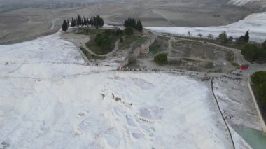 Drone view of Pamukkale travertines, natural beauty consisting of waterfalls and swimming pool with white minerals in Turkey, images of hierapolis tourism center landscapes