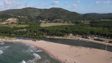 Aerial beachside resorts, beach and relaxation area lying on the shore, camping area intertwined with greenery at the foot of the mountain