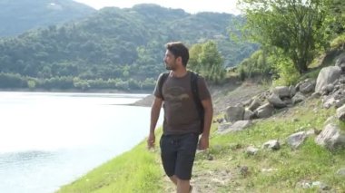 Doğayı keşfeden sırt çantalı gezgin, orman gölü manzaralı gezgin, göl kenarında yürüyen, rahatlamak için ormanda yürüyüş yapan.