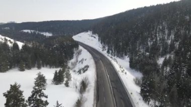Karla kaplı bir ormanda yol manzarası, yüksek dağlardan geçen insansız hava aracı yolu, Sarikamis Kars Türkiye 