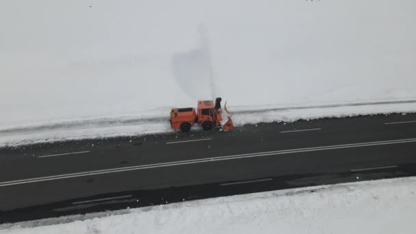 雪に覆われた道路をクリアするために働くピックアップトラックタイプのプロウの空中ドローンビュー 輸送雪の高速道路上で実行されている吹雪 — ストック動画