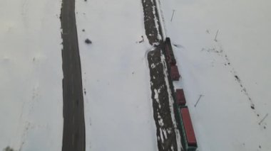 Karla kaplı raylarda giden trenin görüntüsü İHA tarafından çekilen çekim, kışın kargo taşıyan lokomotif, karlı yollardan geçen yük treni manzarası