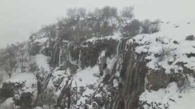 Dağlardan akan doğal Girvelik Şelalesinin, kar kaplı bir kış gününde Giverik Şelalesi 'nin insansız hava aracı görüntüsü, Erzincan Türkiye 