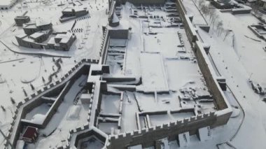 Karların altındaki Erzincan şehrine insansız hava aracı manzarası, Erzurum 'un tarihi kalesine kış manzarası, taştan kale duvarları ve dalgalanan Türk bayrağı.