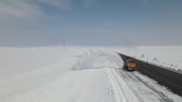 雪上高速道路を走行するトラックの空中ショットビュー 雪の地形でアクセス道路を開く作業機器 冬に高速道路上の重車両の実行 — ストック動画