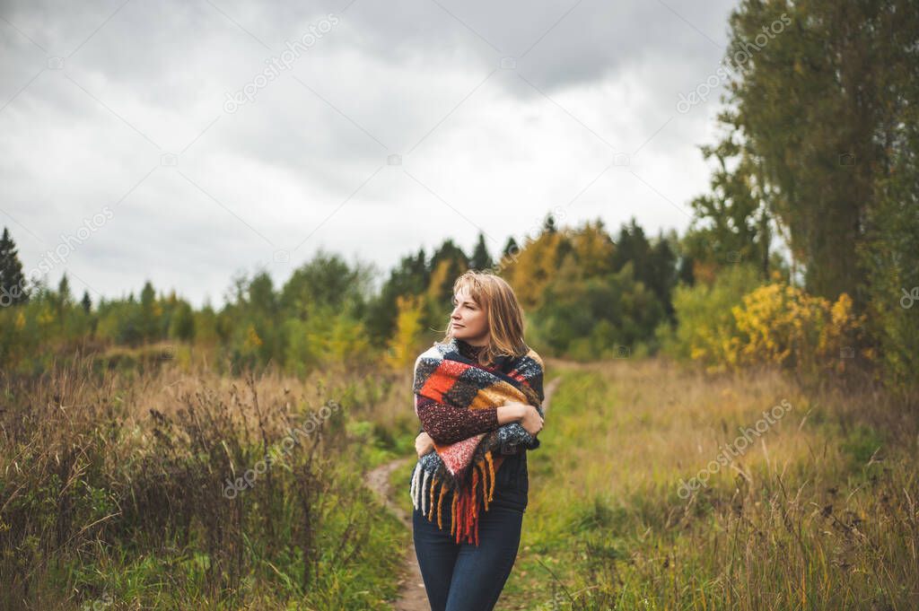 A beautiful woman, blonde meditates and relaxes in the autumn forest. The concept of slow life and unity with nature.