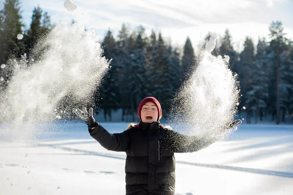Um adolescente brinca com neve na floresta em um dia ensolarado de inverno. Jogos de inverno felizes e um estilo de vida saudável. — Fotografia de Stock