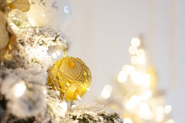 Beyaz altın topla süslenmiş Noel ağacı. Karla kaplı bir ağacın dalında, yumuşak odaklı bir Noel süsü var. Uzayı kopyala Metin için yer