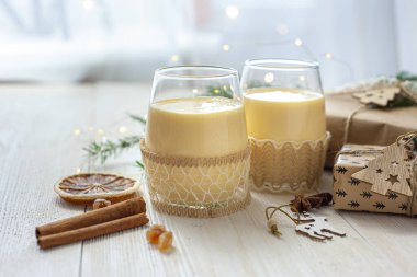Noel hediyelerinin yanındaki beyaz tahta masada iki bardak eggnog. Tatlı yumurta tatlısı. Noel kahvaltısı. Seçici odak