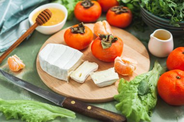 İçindekiler ve hurma, mandalina ve peynirli vitamin kış salatası yapma süreci. Seçici odak