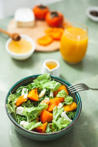 Light sweet and sour salad with persimmon, tangerines and cheese. Winter vitamin salad and ingredients on a White table. Diet food. Selective focus Vegan breakfast or lunch. Dietary nutrition — Stok fotoğraf