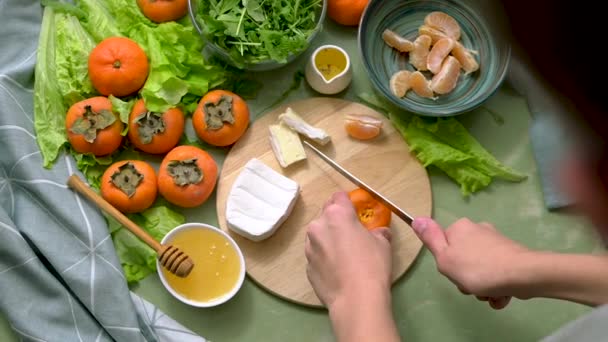 Приготування дієтичного веганського салату від особин, мандаринів і салату. Вид зверху. руху камери. Людські руки нарізають фрукти на здоровий сніданок або обід . — стокове відео