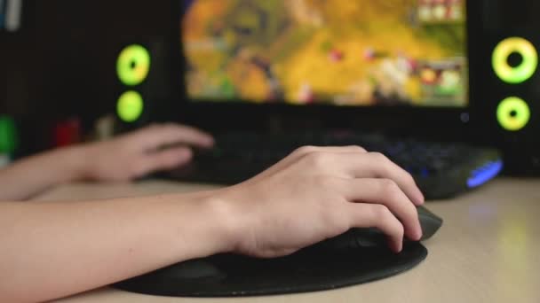 Masada oturmuş bilgisayar oyunu oynayan genç bir çocuk. El fareyi hareket ettirir ve düğmeye basar. Monitör bulanık.. — Stok video