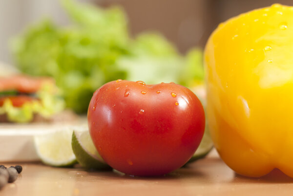 Помидор на кухне в окружении овощей
