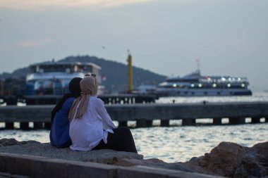 Burka 'daki kızlar Büyükşehir Adası, Türkiye, İstanbul, Adalar Adaları kıyılarında oturuyorlar