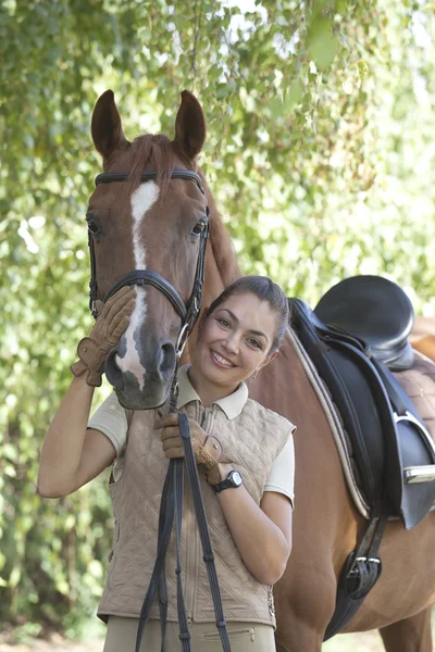 Portrait of a beautiful horsewoman standing with red horse outdo — Stock Photo, Image