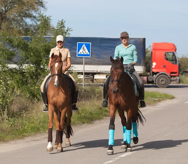 Beautiful smiling womens riding a brown horses in countryside — Stock Photo, Image