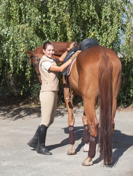 Hermosa chica sonriente con un caballo marrón — Foto de Stock