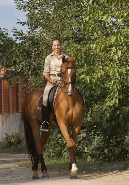 Beautiful smiling women riding a brown horse in countryside — Stock Photo, Image