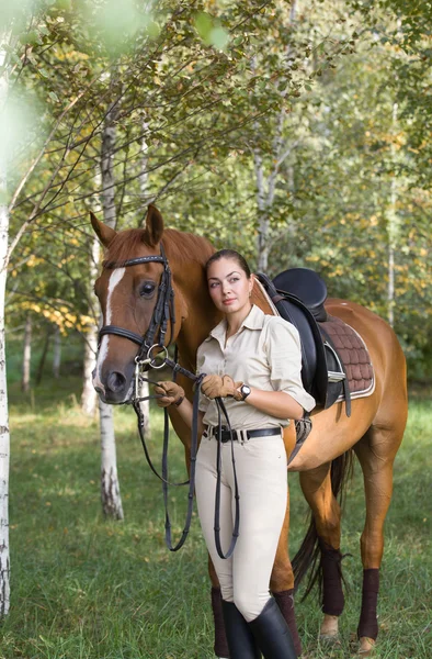 Porträtt av ung vacker brunett kvinna med en brun häst — Stockfoto