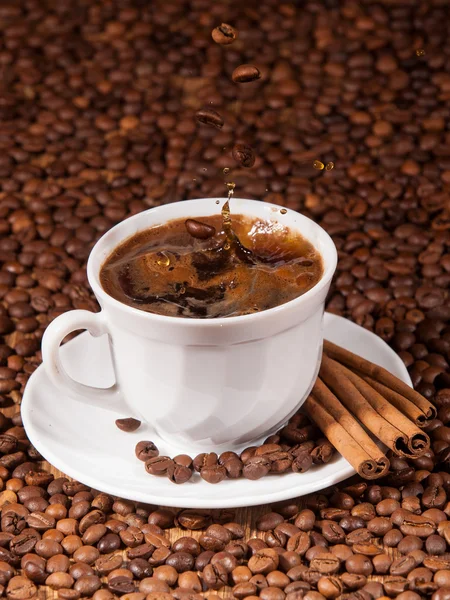 Kaffebönor som faller i en kopp kaffe — Stockfoto