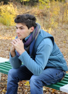 parkta oturan genç adam.