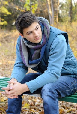 parkta oturan genç adam.