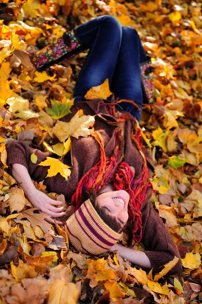 Mädchen liegt im Laub. — Stockfoto