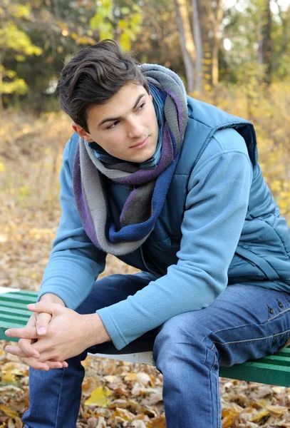 Молодой человек сидит в парке . — стоковое фото