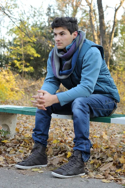 Mladý muž sedí v parku. — Stock fotografie