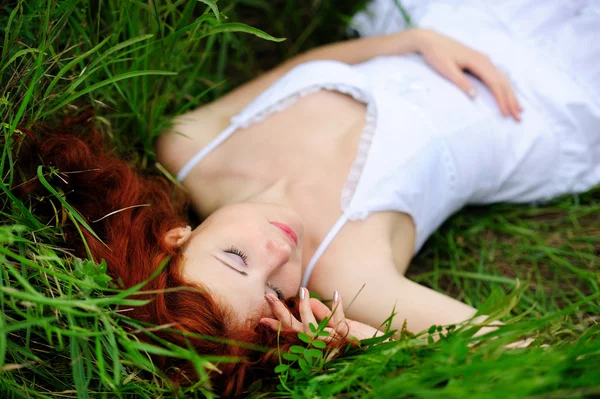 Meisje portret, liggend in grasveld. — Stockfoto