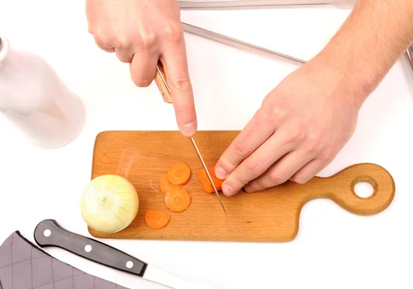 Mannenhand snijden uien en wortel op houten bord — Stockfoto