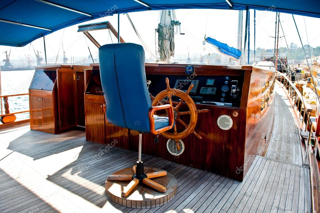 Cockpit inside a boat with a wood wheel.