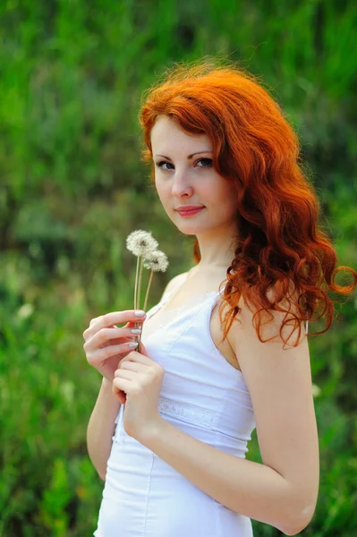 Jonge redhead vrouw met paardebloemen. — Stockfoto