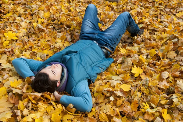 Junger Mann liegt im Laub. — Stockfoto