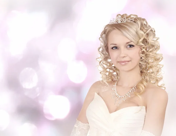 Smiling young bride on light bokeh background. — Stock Photo, Image