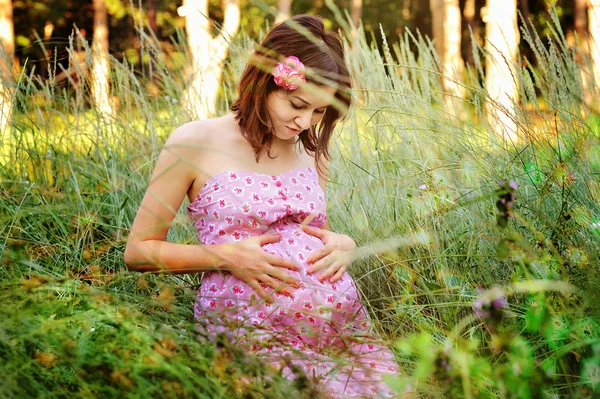 Mulher grávida relaxando em uma grama . — Fotografia de Stock